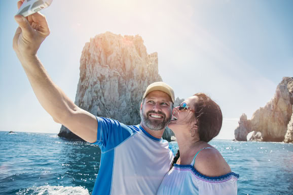 Couple capturing a travel moment by the water, emphasizing memory-making and destination appeal.